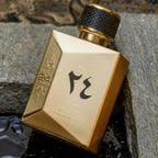 Gold perfume bottle with black cap on a textured surface