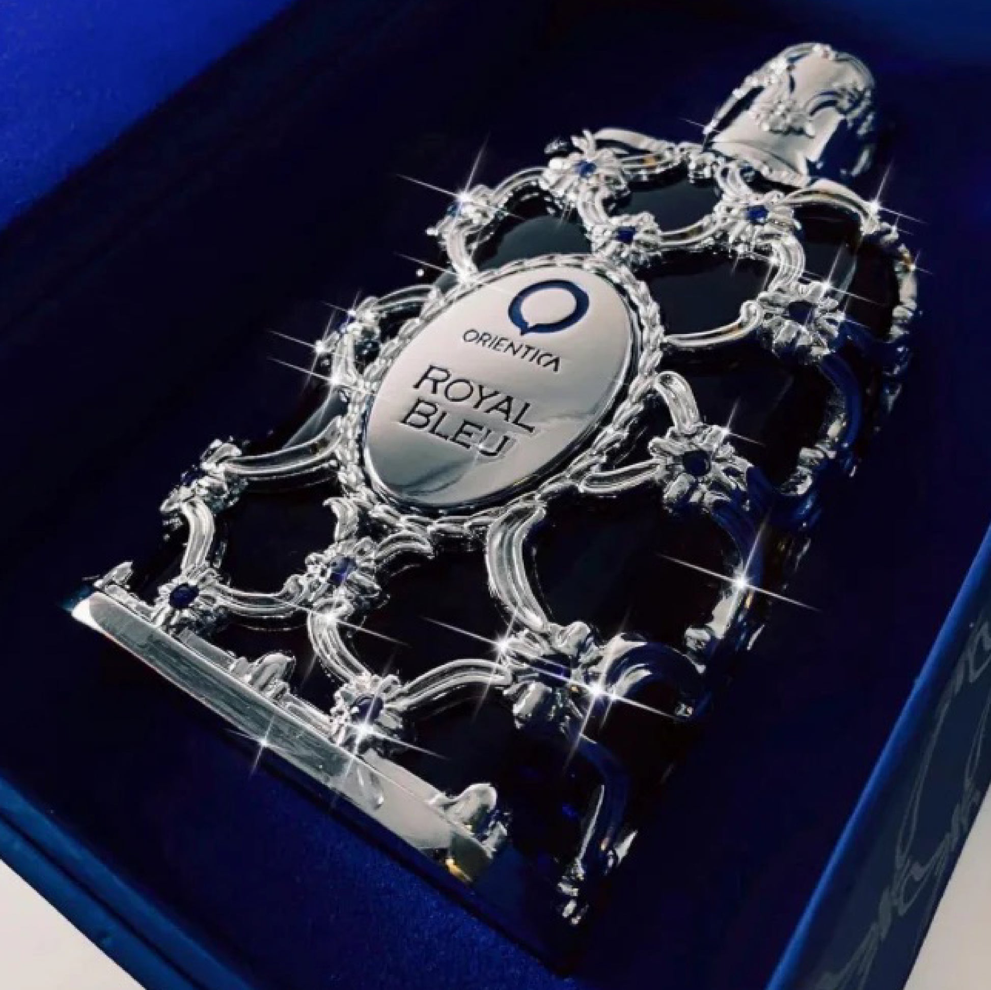 Oriflame Orienta Royal Bleu perfume bottle with intricate design on a blue background