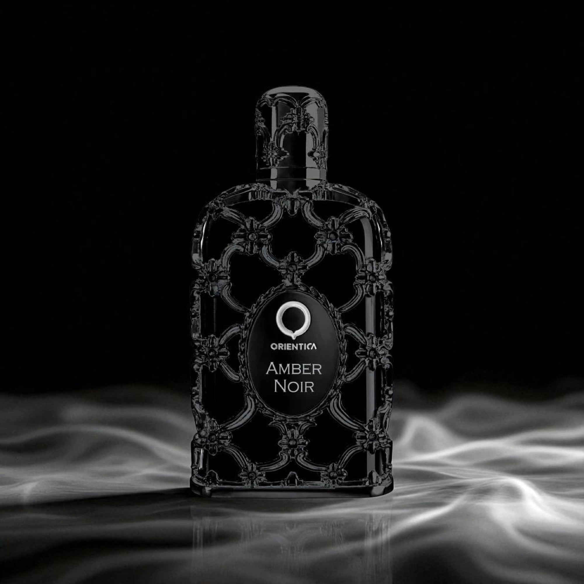 Perfume bottle labeled 'Orienta Amber Noir' on a dark background with smoke effects.