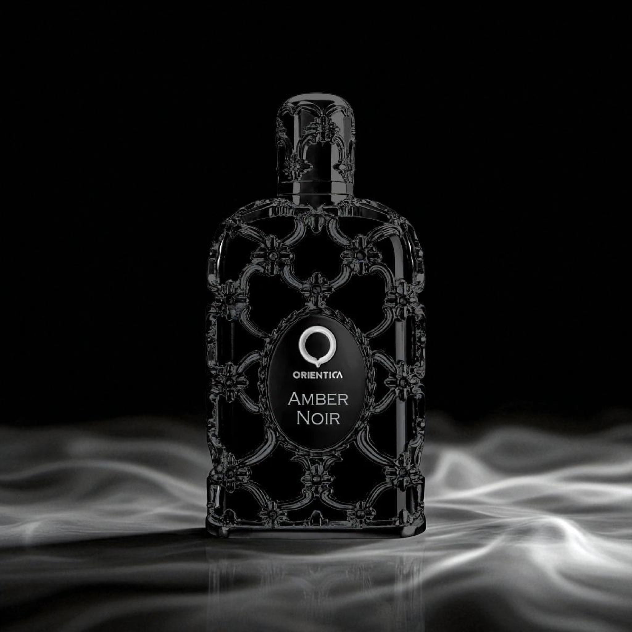 Perfume bottle labeled 'Orienta Amber Noir' on a dark background with smoke effects.