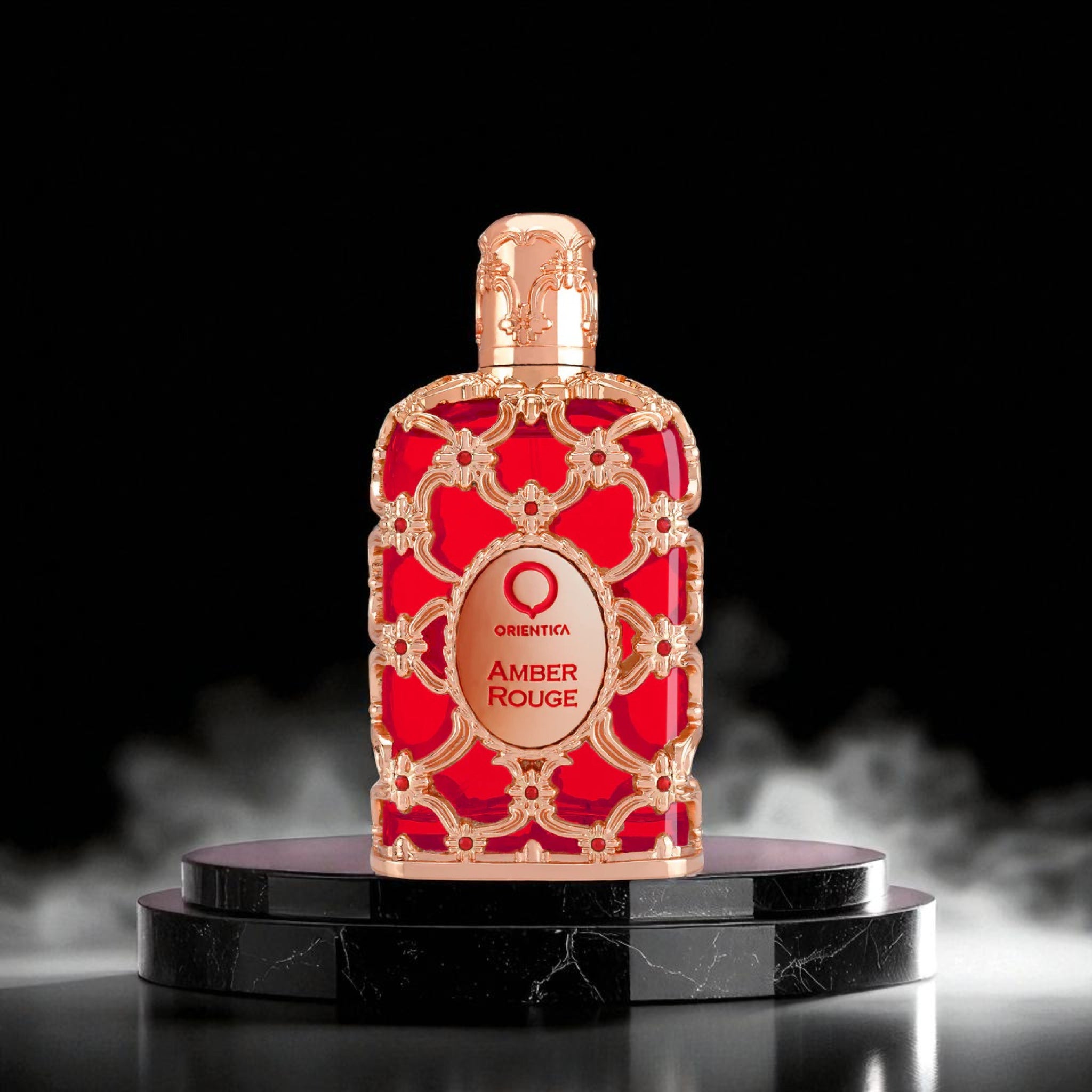 Red and gold perfume bottle labeled 'Amber Rouge' on a black platform with a dark background