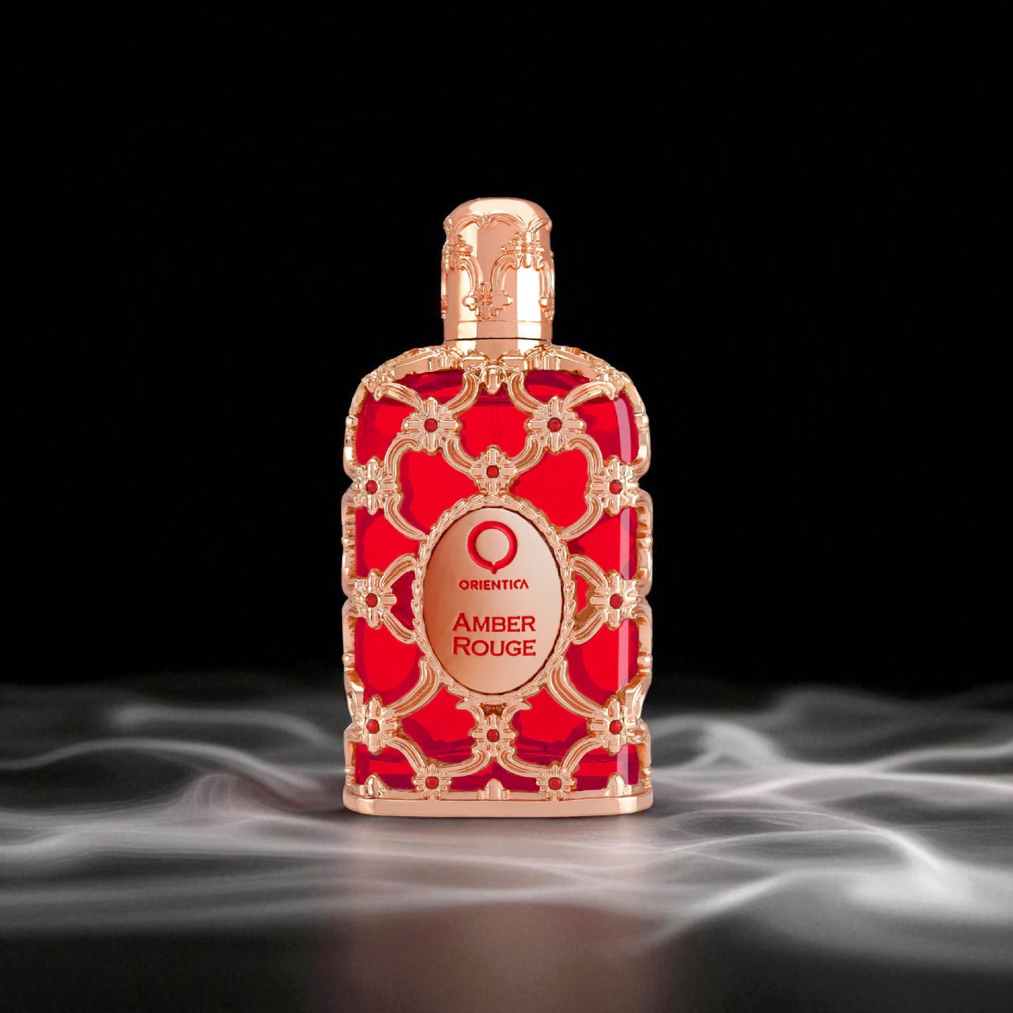 Red and gold perfume bottle labeled 'Amber Rouge' on a dark background