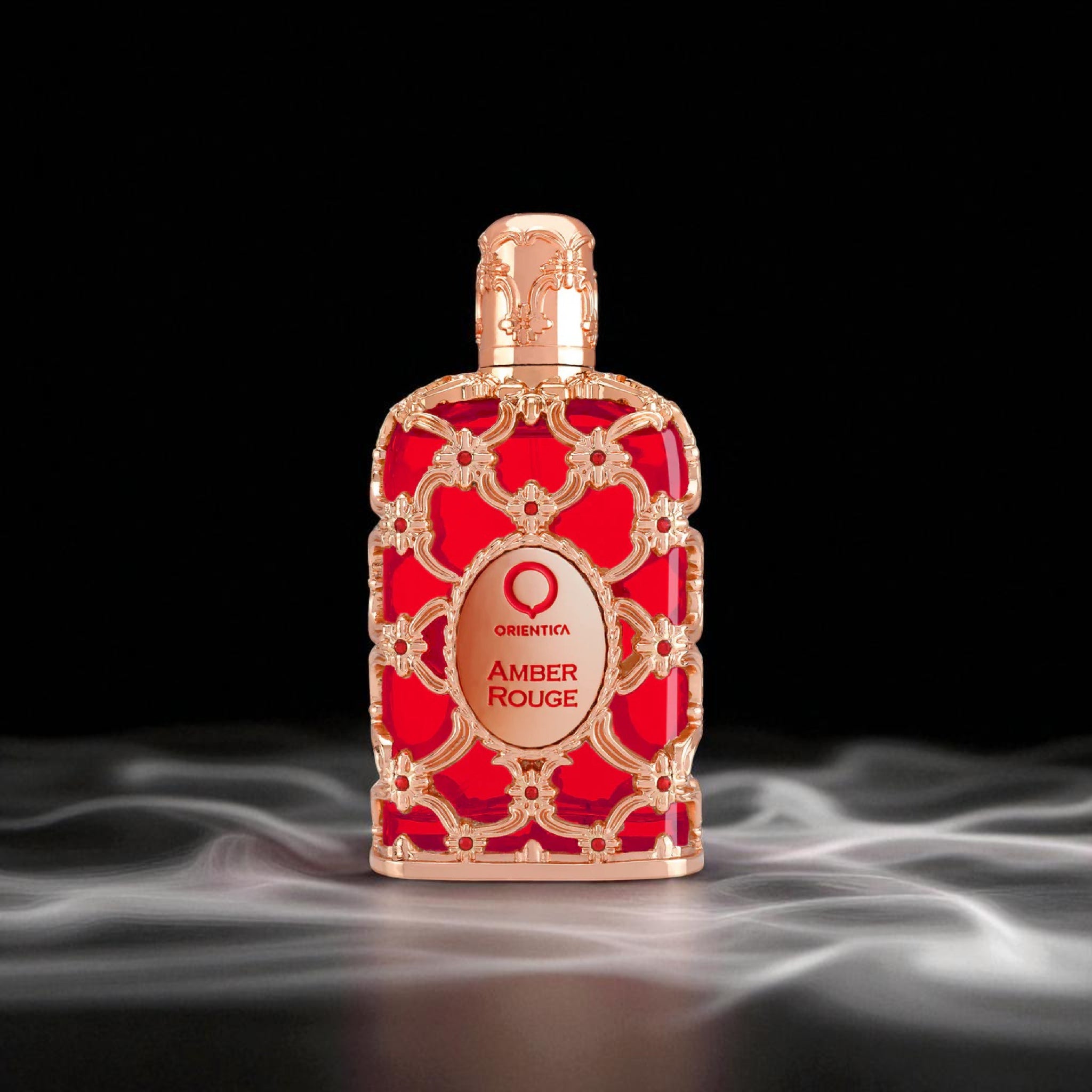 Red and gold perfume bottle labeled 'Amber Rouge' on a dark background