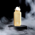 Gold Elysia perfume bottle on a black platform with smoke effects
