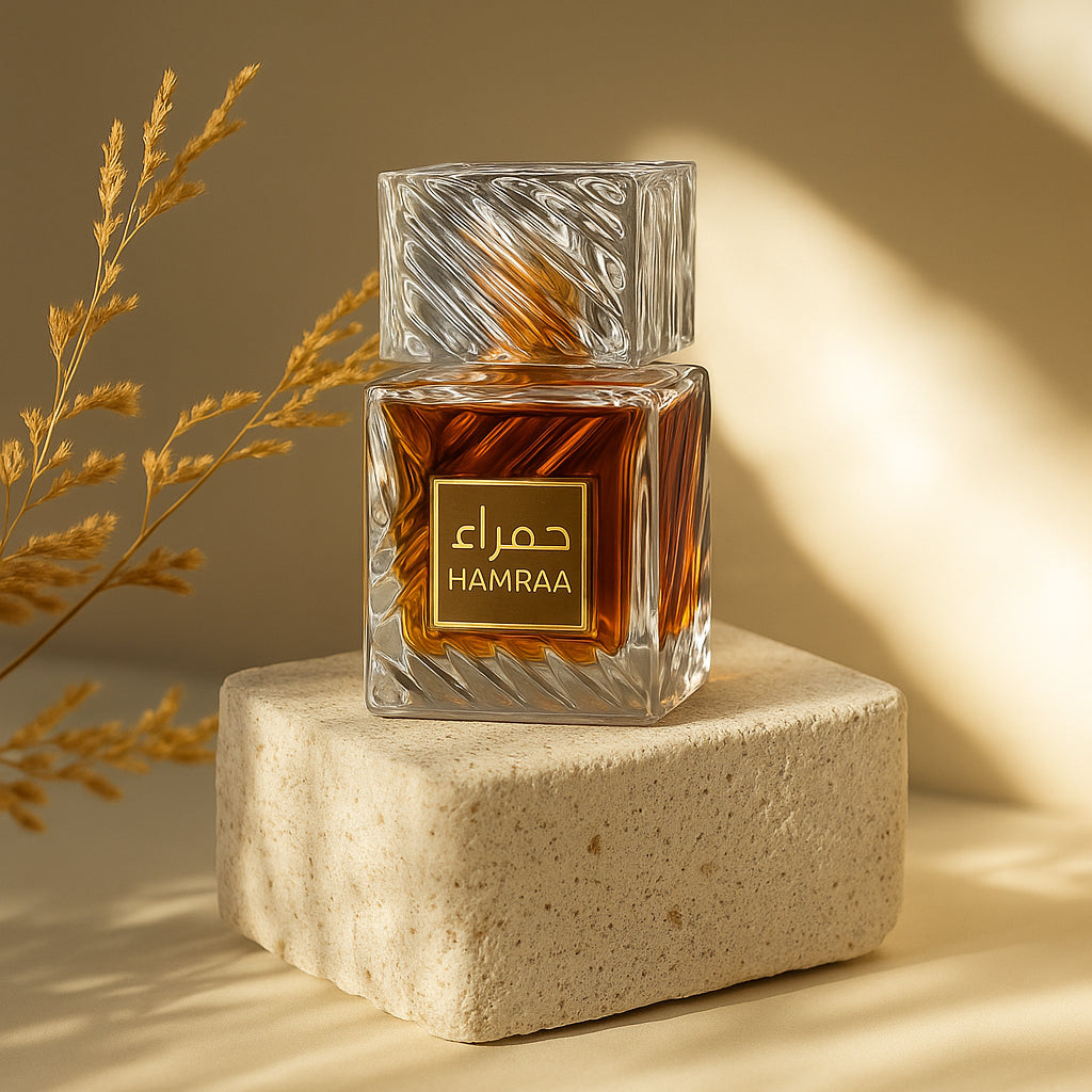 Hamraa perfume bottle on a stone platform with a dried plant on a beige background
