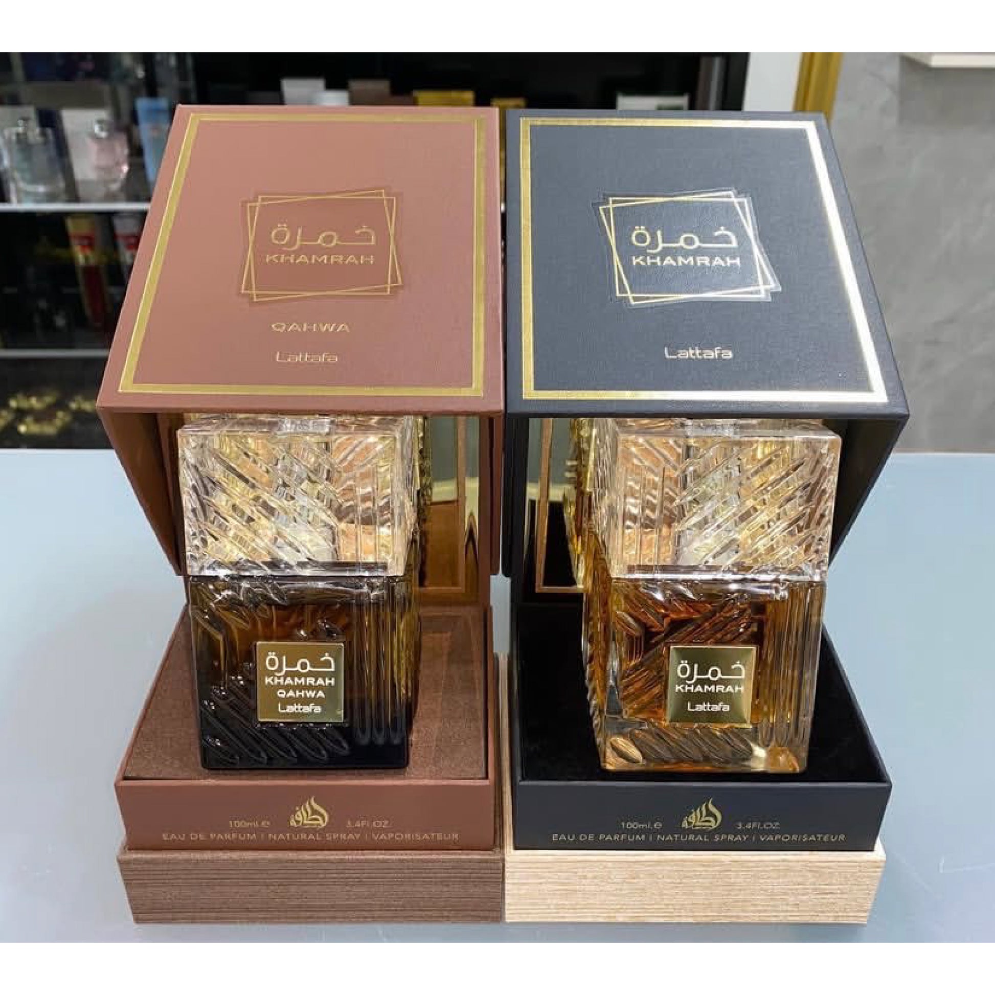 Two Khamrah Lattafa perfume bottles in their packaging on a reflective surface.