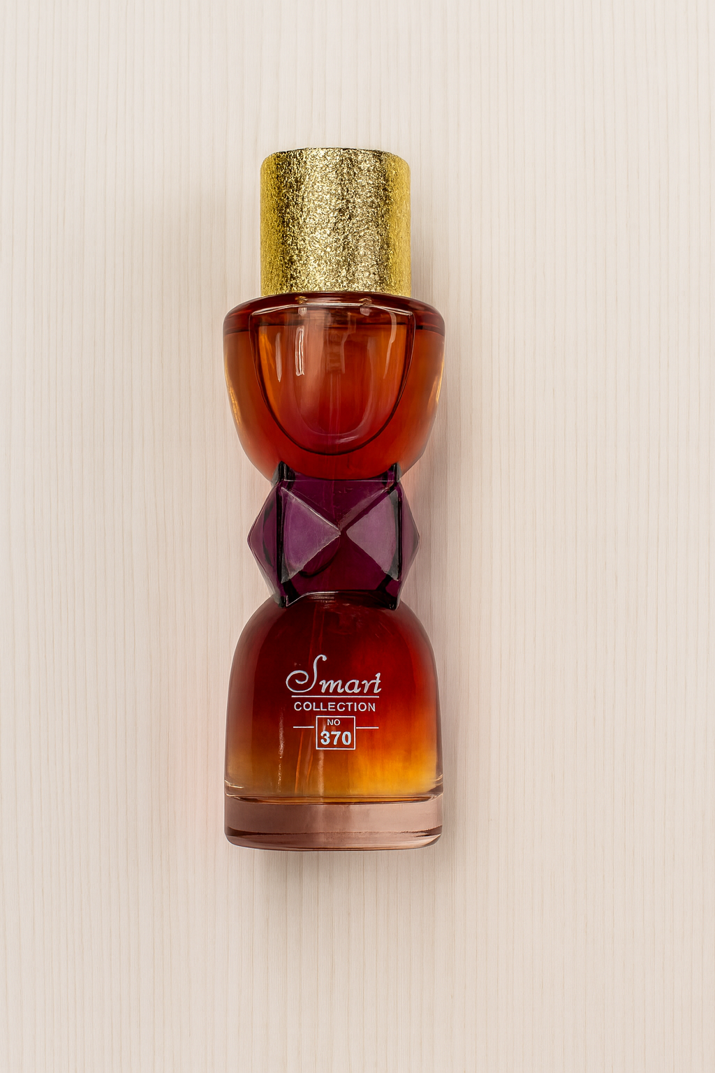 Decorative bottle with a gold cap and intricate design on a beige background